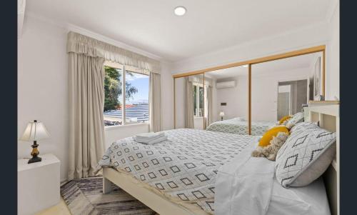 a white bedroom with a large bed and a window at Sarovar Holidays in Traralgon