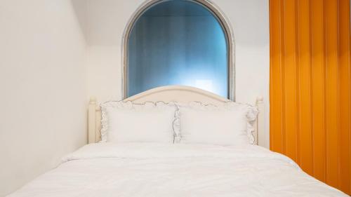 a bedroom with a white bed with an ornate headboard at Chuncheon Vishop Pension in Chuncheon