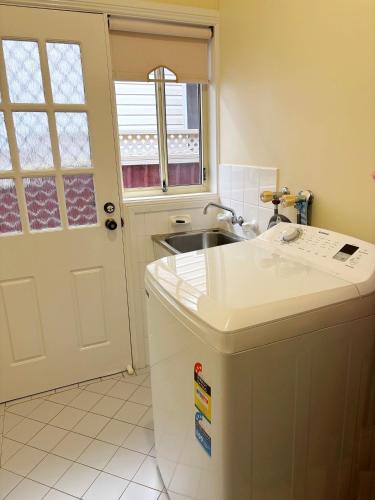 a kitchen with a sink and a white door at Chalkers Unit - Bring your own linen in South West Rocks