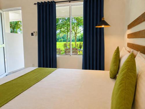a bedroom with a large bed with blue curtains at Thisara Guest House in Polonnaruwa
