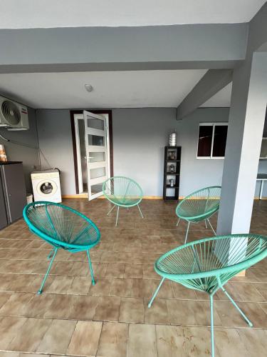 a room with three green chairs and a table at Charming house in a natural setting in Sainte-Rose