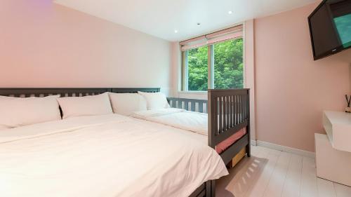 a bedroom with two beds and a window at Gapyeong Pogny Kids Poolvilla in Gapyeong