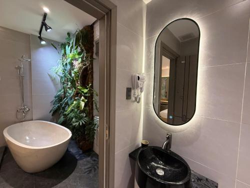 a bathroom with a tub and a sink and a mirror at Palm Hotel in Tam Kỳ