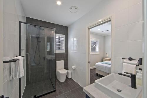 a bathroom with a shower and a toilet and a sink at Serenity Place in Mannering Park