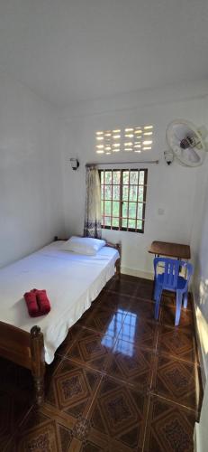 a bedroom with a bed and a table and windows at Khmer House Guesthouse in Kep
