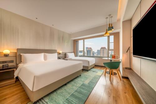 a hotel room with two beds and a flat screen tv at Holiday Inn Shanghai Nanjing Road by IHG in Shanghai
