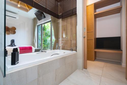 a bathroom with a large tub and a television at Tropical Private Pool Villa Dalaa 9 in Kamala Beach