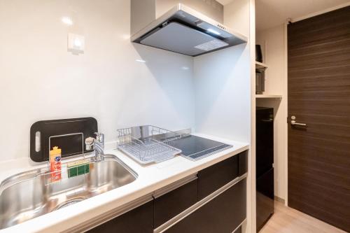 a kitchen with a sink and a microwave at ReLA Minami-Nagareyama in Nagareyama