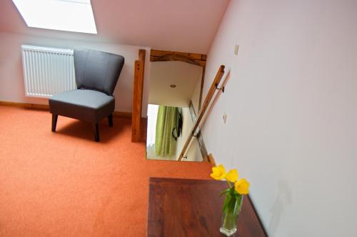 a room with a chair and a table and a vase of flowers at Vila Pod Bránou in Poprad