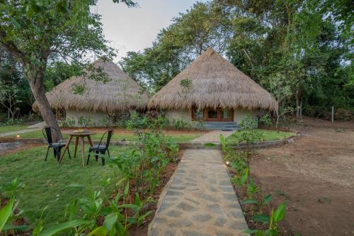 two huts with a table and chairs in front of it at Tranquil Trails Sigiriya in Dambulla