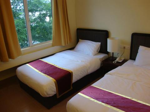 two beds in a room with a window at DM Hotel in Kota Kinabalu