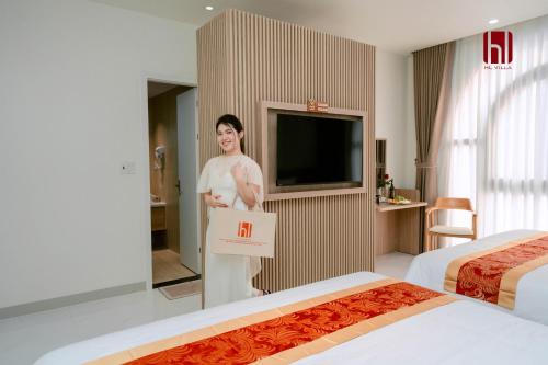 a woman holding a sign in a hotel room at HL Villa in Dong Hoi