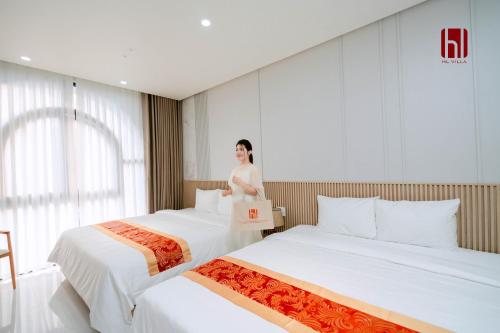 a woman standing between two beds in a hotel room at HL Villa in Dong Hoi