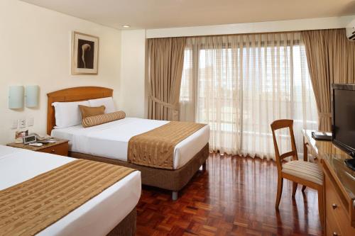 a hotel room with two beds and a television at City Garden Suites Manila in Manila