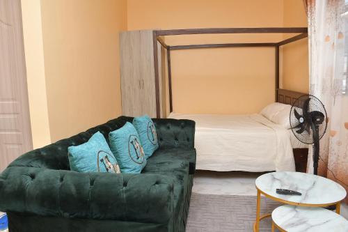 a living room with a green couch and a bed at Maria Villa Studio in Voi