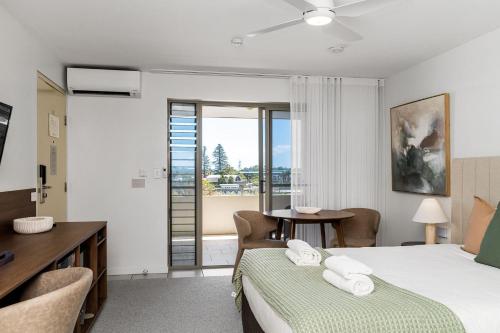 a bedroom with a bed and a desk and a table at Riverside Apartments & Hotel in Ballina