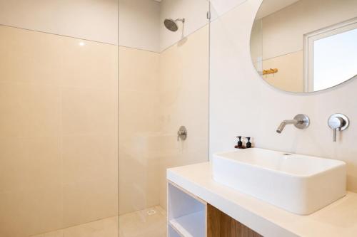 a white bathroom with a sink and a mirror at Double A Cozy Living in Canggu