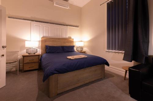 a bedroom with a bed with blue sheets and two lamps at The Stapleton in Kalgoorlie