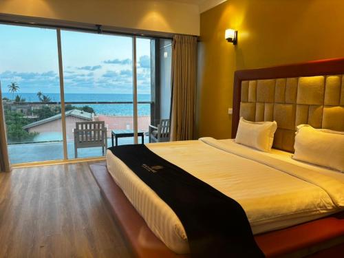 a bedroom with a large bed with a view of the ocean at Mazarin Hiriketiya in Dickwella