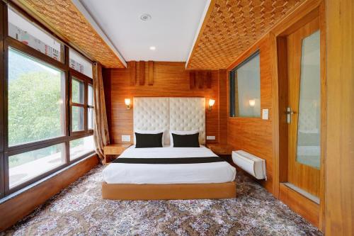 a bedroom with a large bed in a room with windows at Palette Hotel Regency Valley View Pahalgam By CheckIn in Batakūt