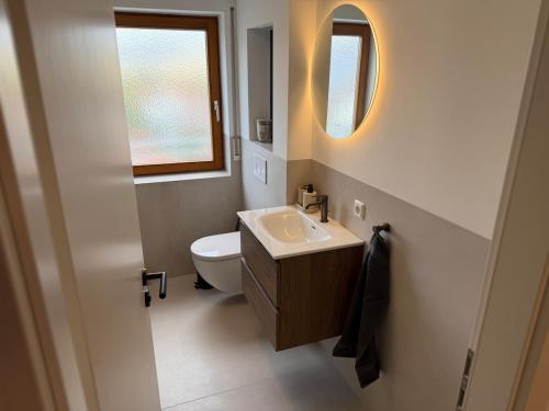 a bathroom with a sink and a toilet and a mirror at Modernes Apartment mit Balkon in Wutöschingen