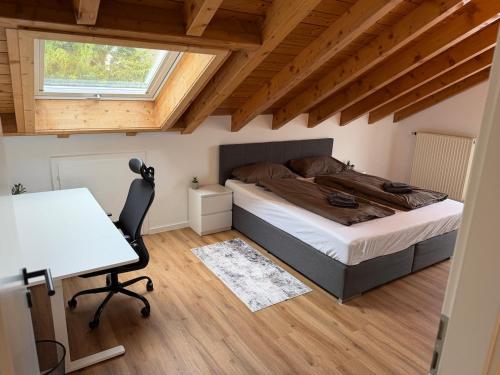 a bedroom with a bed and a desk and a window at Modernes Apartment mit Balkon in Wutöschingen