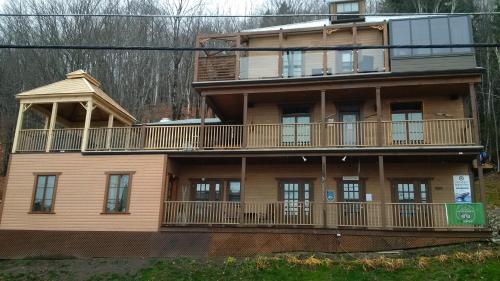 a large wooden building with a balcony on it at Auberge Le Four à Pain in Petite-Rivière-Saint-François