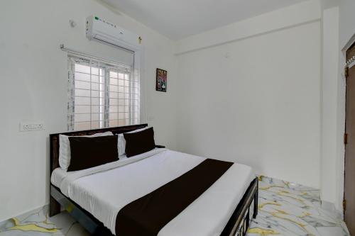 a bedroom with a bed in a room with a window at Super Hotel O Gandimaisamma Thalli Temple Formerly GN Luxury Suits in Dhundgol