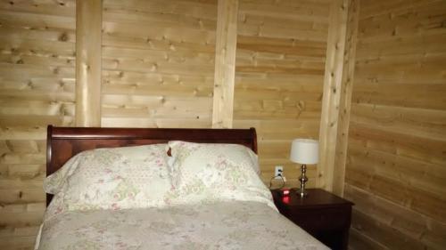 a bedroom with a bed and a wooden wall at Auberge Le Four à Pain in Petite-Rivière-Saint-François