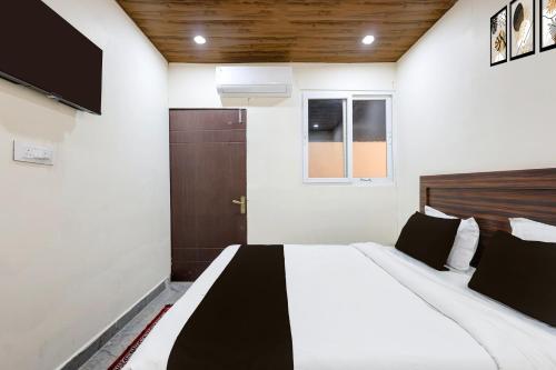 a bedroom with a large bed with black and white sheets at Hotel O Uttaranchal University Dehradun in Jhājra
