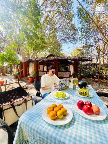 a man sitting at a table with plates of fruit at The Hideaway Hosur by evaddo stays in Hosūr