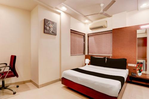 a bedroom with a bed and a chair and a window at Townhouse Oak Ramdaspeth Downtown in Nagpur