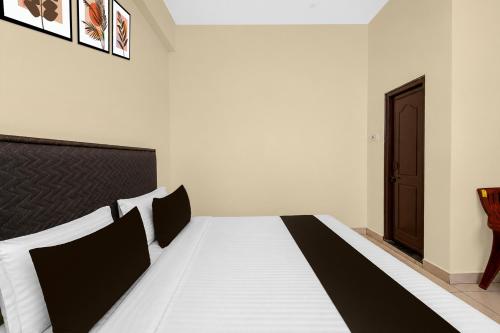 a bedroom with a black and white bed in a room at Super Hotel O Temple Road Vemulavada in Karīmnagar