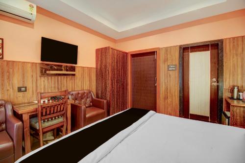 a bedroom with a bed and a desk and a television at Collection O Downtown Hospital Guwahati Formerly Cherry City Cottage in Guwahati