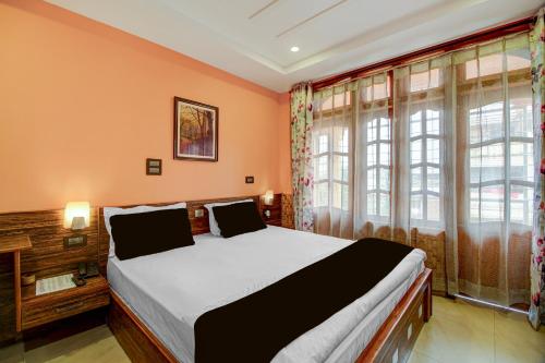 a bedroom with a bed with orange walls and windows at Collection O Downtown Hospital Guwahati Formerly Cherry City Cottage in Guwahati