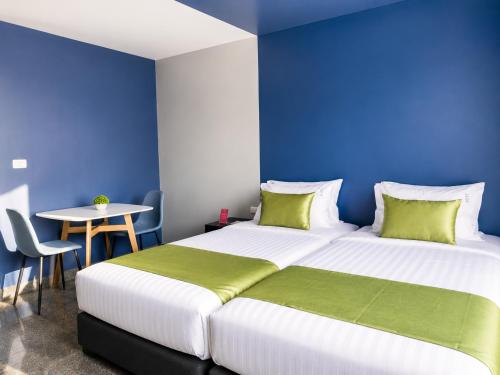 two beds in a room with blue walls and a table at iCheck inn Phuket Town in Phuket