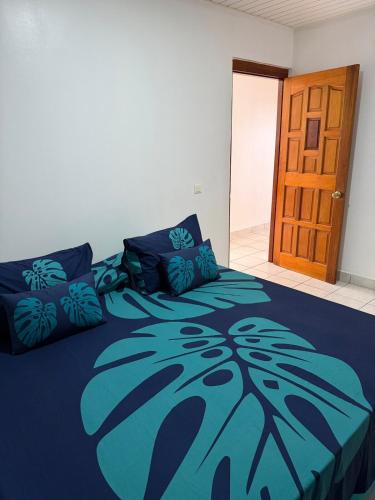 a bedroom with a bed with a blue comforter at Fare Havai - Raiatea in Taputapuapea