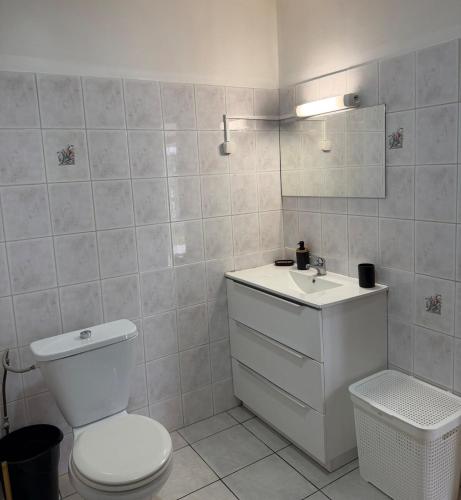 a white bathroom with a toilet and a sink at Fare Havai - Raiatea in Taputapuapea