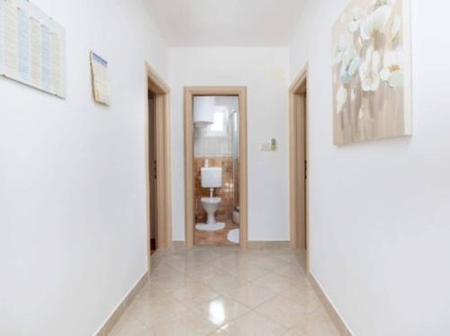 a hallway with a bathroom with a toilet and paintings at Vacation home Marin in Vinišće
