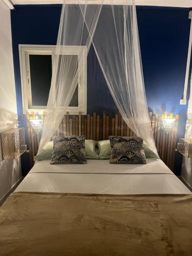 a bedroom with a bed with a canopy and pillows at LaKour Fleurie Chambres d hôtes in Sainte-Rose
