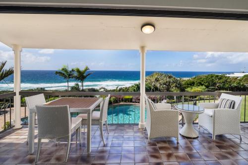 a patio with a table and chairs and the ocean at Sunseeker Holiday Apartments in Sunshine Beach
