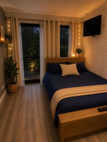 a bedroom with a bed and a television and windows at Garden Studio with Private Patio in Wentworth Falls