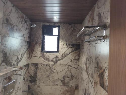 a bathroom with a window and a marble wall at Hotel Radhika in Lātūr