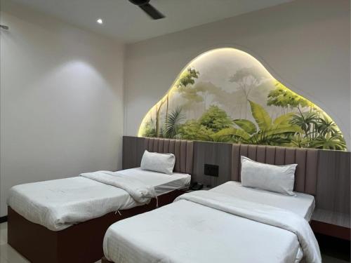 two beds in a room with a painting on the wall at Hotel Radhika in Lātūr