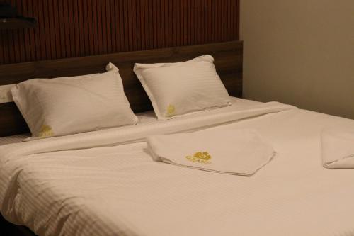 a white bed with white pillows and a napkin on it at Grand Heritage in Ernakulam