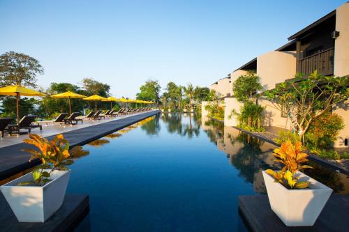 a river with chairs and umbrellas next to a hotel at The ShellSea Krabi I Luxury Beach Front Resort & Pool Villa in Ao Nam Mao