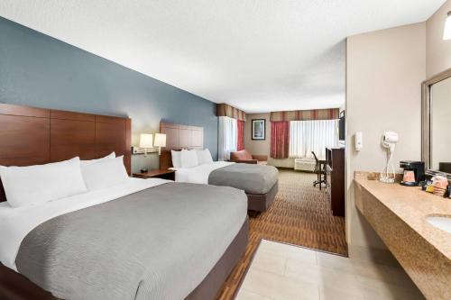 a hotel room with two beds and a bathroom at Quality Inn & Suites Lawrence - University Area in Lawrence