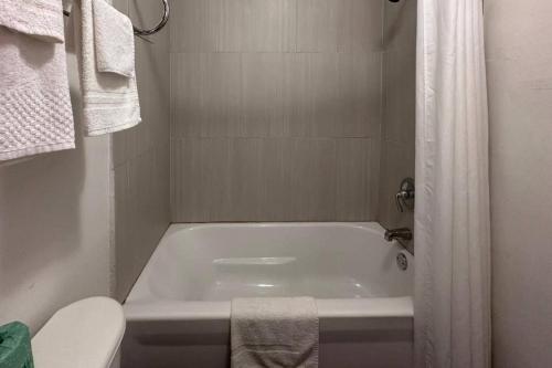a white bathroom with a tub and a toilet at Rodeway Inn Flora in Flora