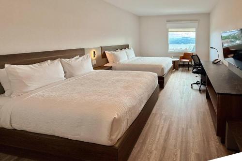 a hotel room with two beds and a desk at Quality Inn & Suites Temiscouata-sur-le-Lac in Notre-Dame-du-Lac