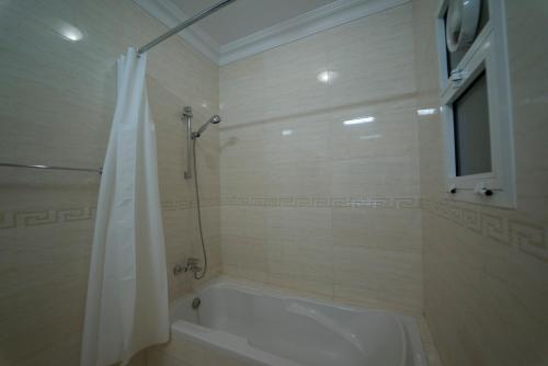 a bathroom with a tub and a shower with a shower curtain at Al Ghubrah Plaza Hotel in Muscat
